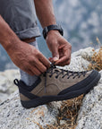 Close-up of DANNTO Veld I khaki barefoot shoes hiking shoe being tied on a rocky surface