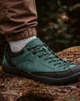 Close-up of DANNTO Veld I green   barefoot shoes worn outdoors on a moss-covered log