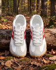 DANNTO Purus Men's and Women's Wide Toe Box Barefoot Shoes in White Shown Side by Side on a Forest Floor in Front of a Fallen Log.