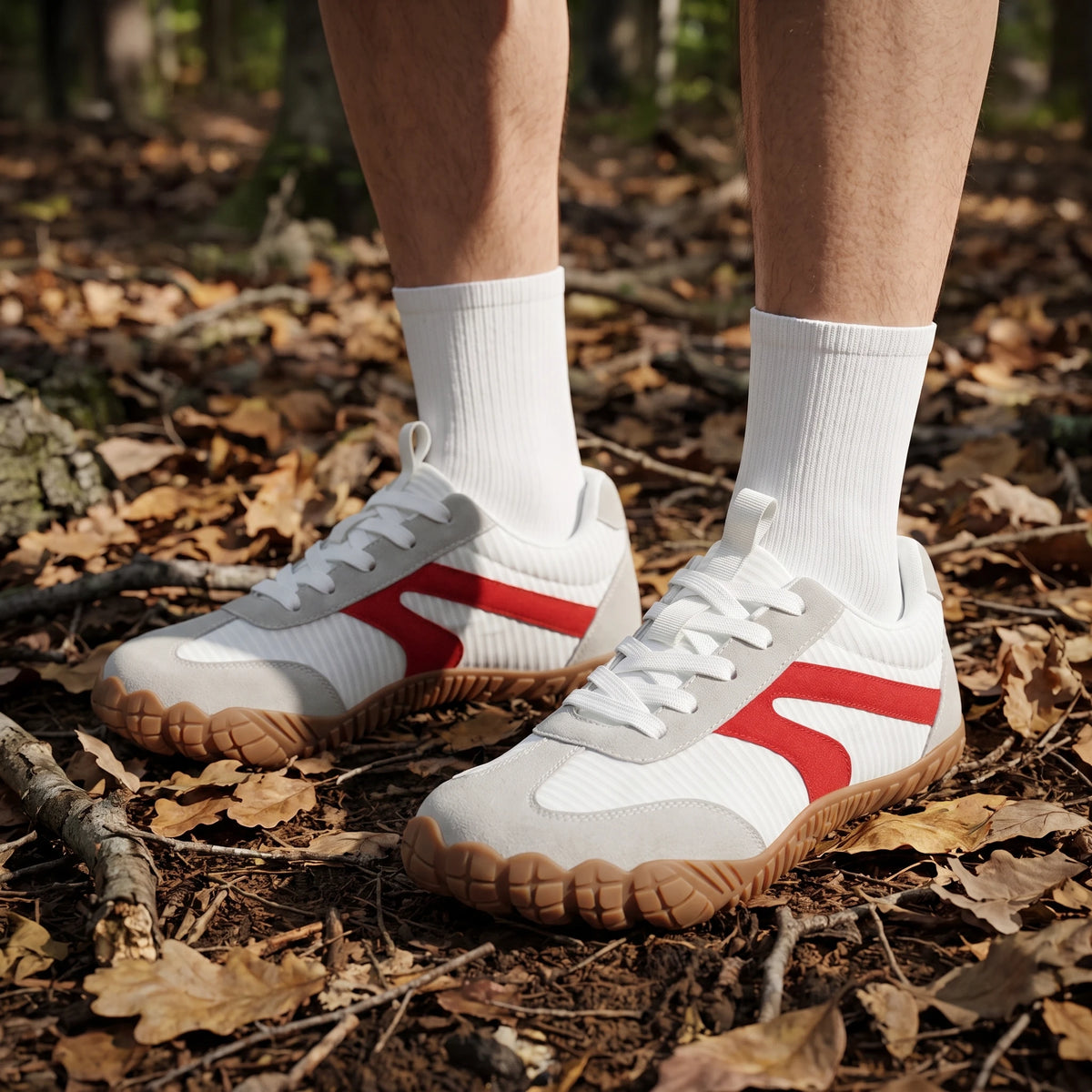 DANNTO Purus Men's and Women's Wide Toe Box Barefoot Shoes in White Worn While Standing on a Leaf-Covered Forest Floor.