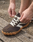DANNTO Purus Men's and Women's Wide Toe Box Barefoot Shoes in Brown Shown Being Tied While Sitting Outdoors.