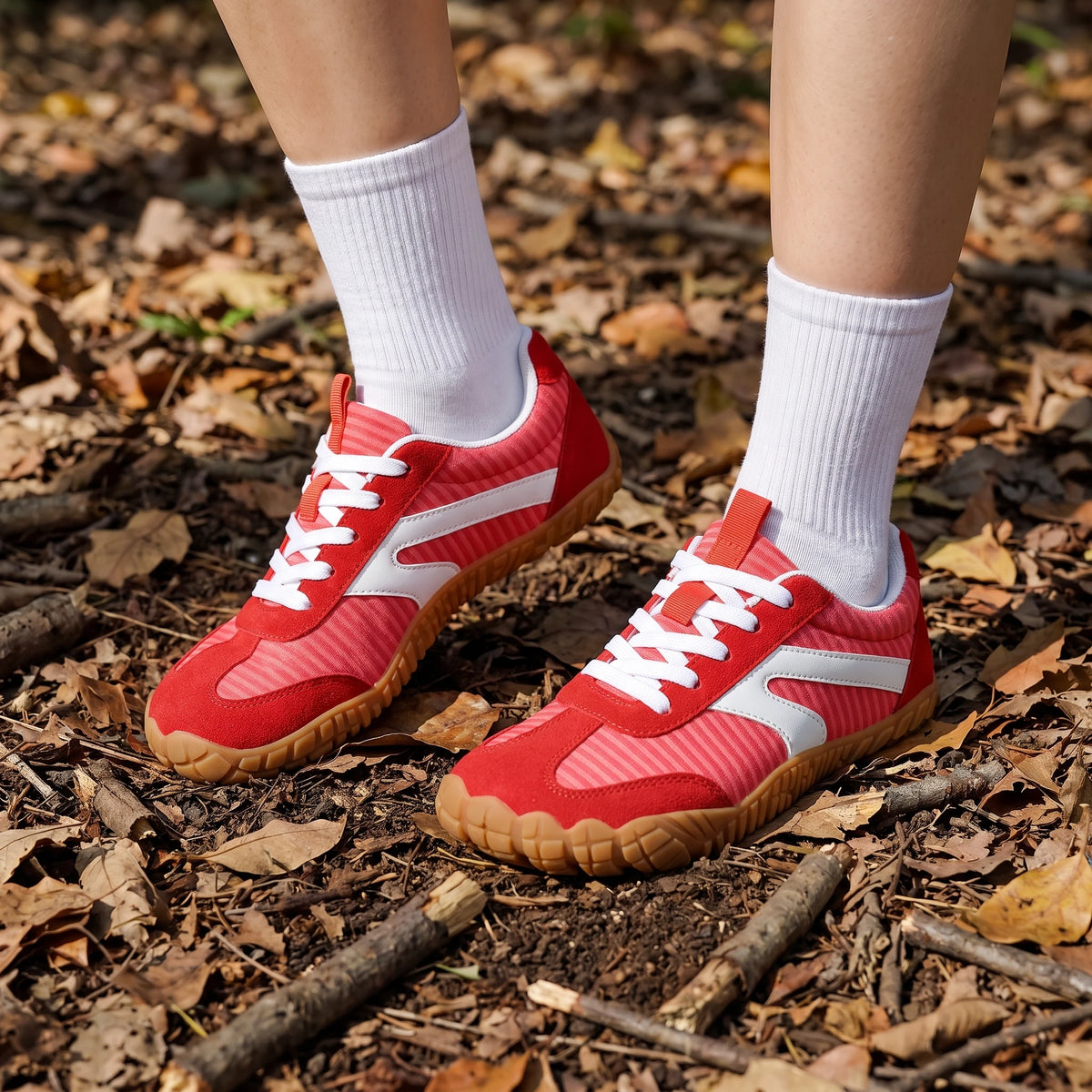 DANNTO Purus Men's and Women's Wide Toe Box Barefoot Shoes in Red Worn While Standing on a Leaf-Covered Forest Floor.
