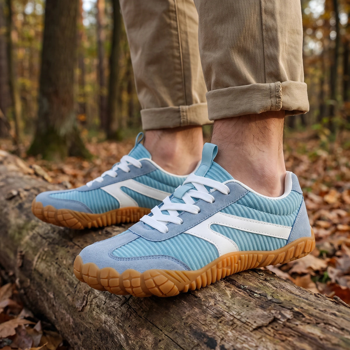 DANNTO Purus Men's and Women's Wide Toe Box Barefoot Shoes in Blue Worn While Walking Across a Fallen Log in a Forest.