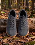 DANNTO Men's and Women's Wide Toe Box Barefoot Shoes in Gray Shown Side by Side on a Forest Floor in Front of a Fallen Log.
