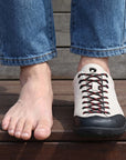 Dannto Veld I Pro - 3E Wide Barefoot Shoes beige shown on one foot beside a bare foot to demonstrate the wide toe box