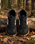 DANNTO Purus Men's and Women's Wide Toe Box Barefoot Shoes in Black Shown Side by Side on a Forest Floor in Front of a Fallen Log.