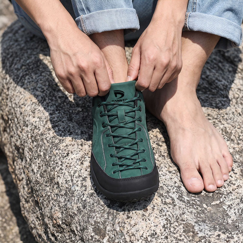 Dannto Veld I - Men's and Women's Wide Toe Box Barefoot Shoes green shown being put on while sitting on a rock outdoors