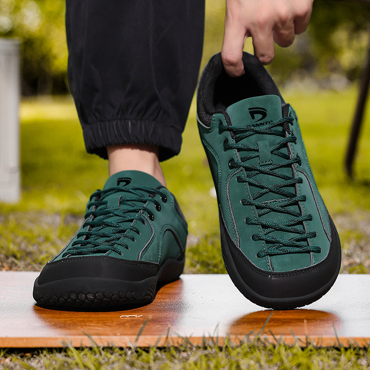 Dannto Veld I - Men's and Women's Wide Toe Box Barefoot Shoes green shown with one shoe worn and the other held by the heel outdoors