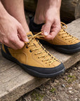 Dannto Veld I - man tying the laces of 3E wide toe box barefoot shoes in tan in outdoors